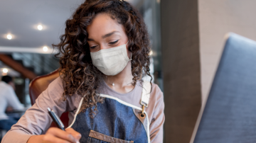Young woman filling out paperwork with mask