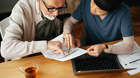 person helping an elderly person with a form