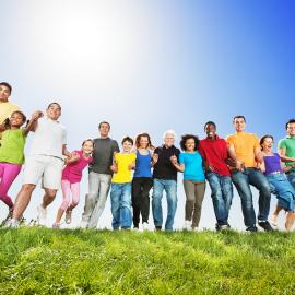 Large group of people holding hands in a field 